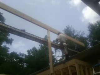Carpenter setting a ridge beam over a new addition frame — Ice Dam Removal by Roofing Brothers in Kendleton