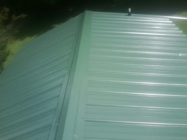 New green metal panels meeting at the ridge of a roof — Flat Roof Repair work by our crew in Kendleton