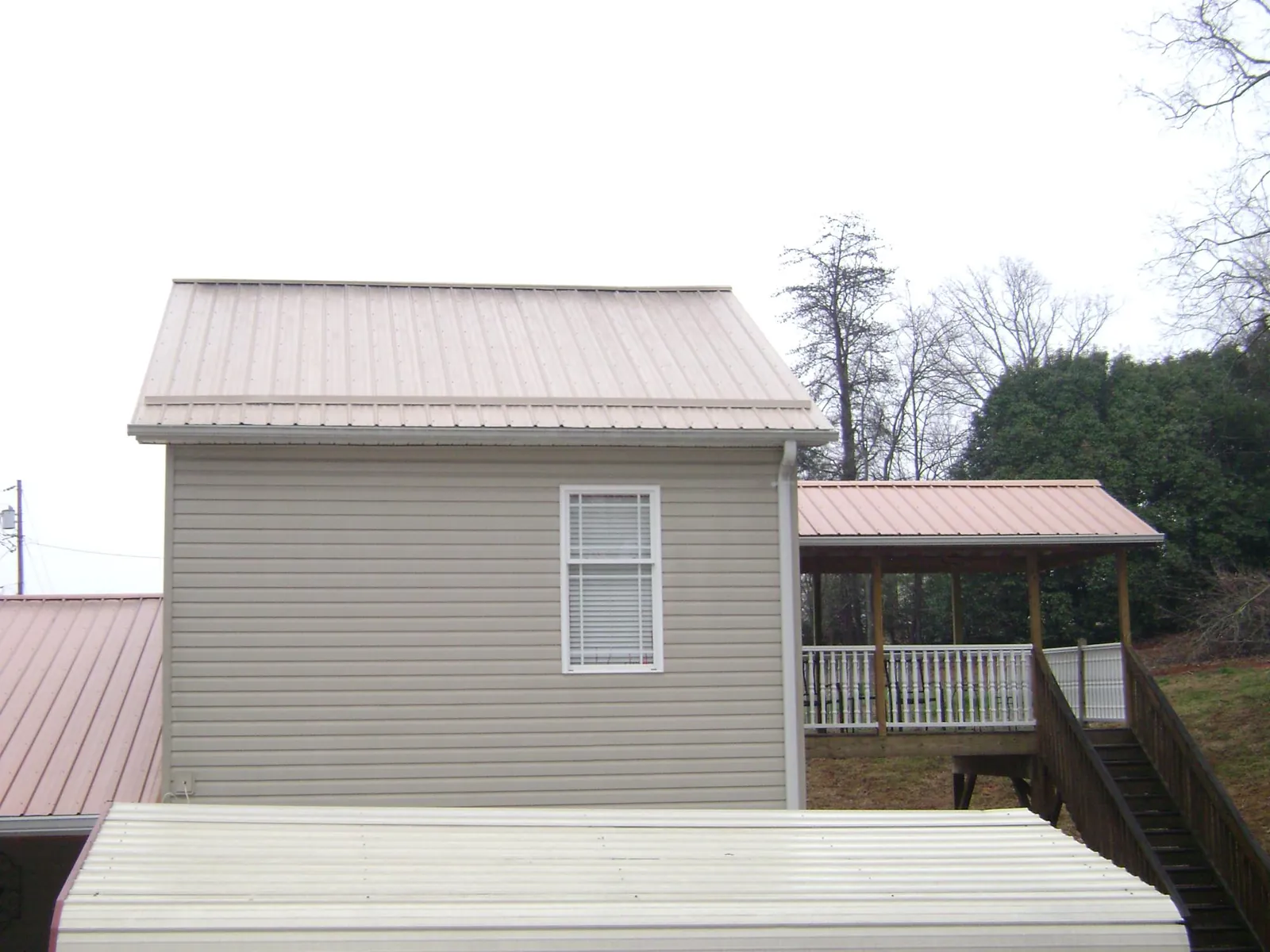 Tan metal roofs on a two story addition and attached porch, from a Roof Replacement job in Kendleton